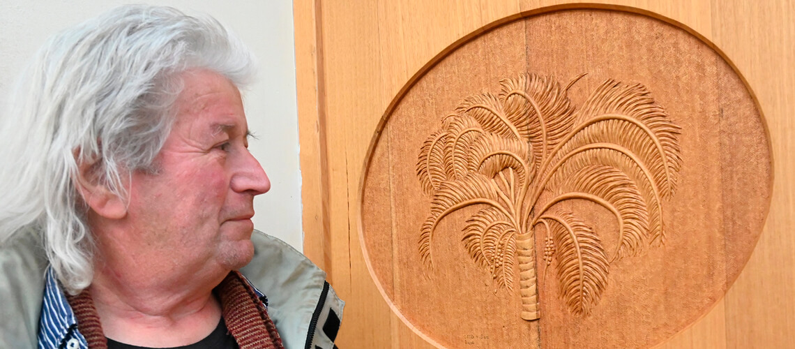 Laurens Otto, wood carver, admires his own work on the Museum door